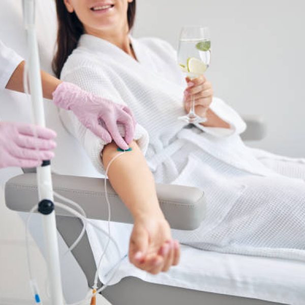 Cropped photo of a woman with a glass of drink sitting in a cosmetic chair