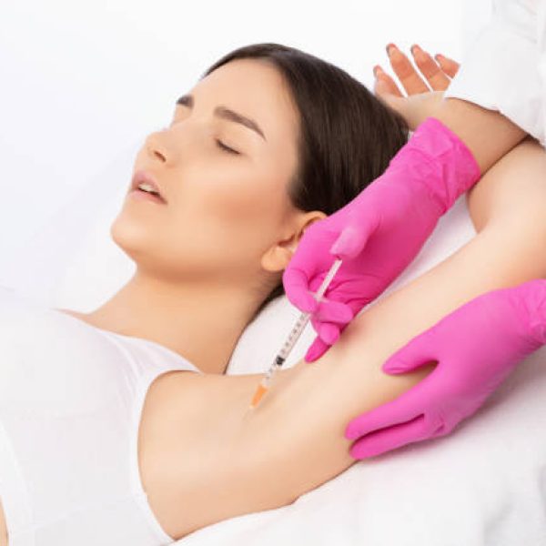 The doctor makes injections of botulinum toxin in the underarm area against hyperhidrosis. Women's cosmetology concept.