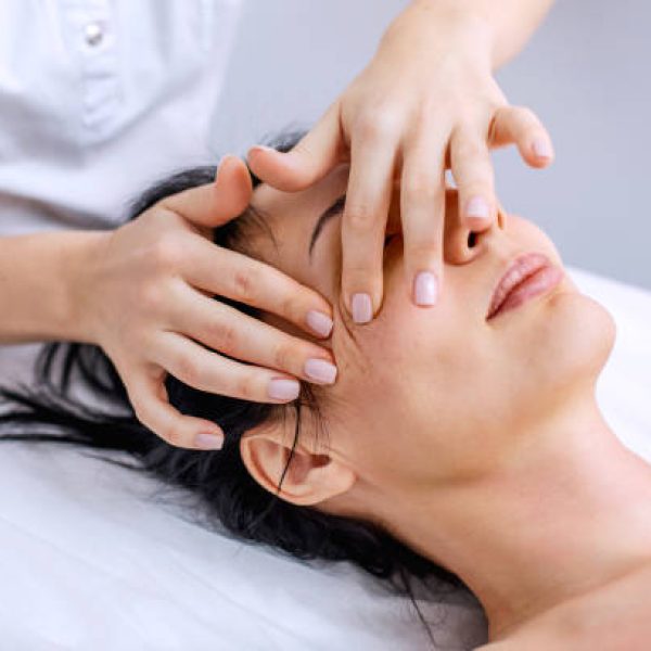 Face and head massage for a young woman. Alternative health methods with aromatic oils. Cosmetology procedures for face and body skin. Skin care in adulthood. Horizontal photo of people.